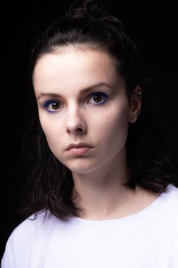 Siyah arka planda beyaz elbiseli mavi makyajlı güzel bir kız.