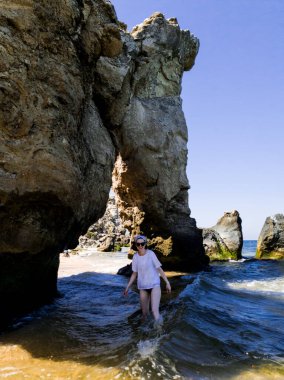 Kayalık sahilde beyaz tişörtlü bir kız.