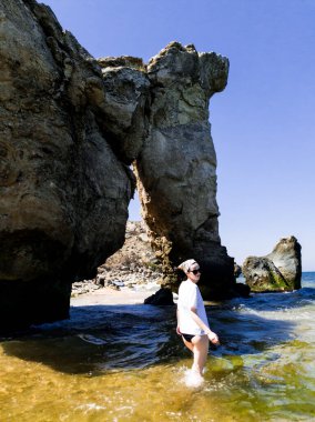 Kayalık sahilde beyaz tişörtlü bir kız.