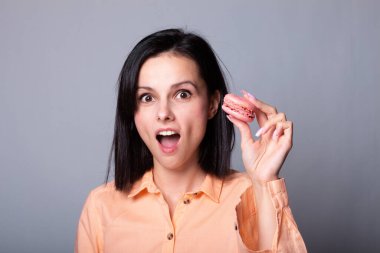 Turuncu gömlekli kadın elinde kurabiye tutuyor.