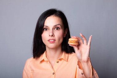 Turuncu gömlekli kadın elinde kurabiye tutuyor.