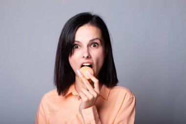 Turuncu gömlekli kadın elinde kurabiye tutuyor.