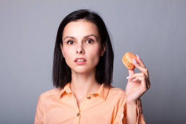 Turuncu gömlekli kadın elinde kurabiye tutuyor.