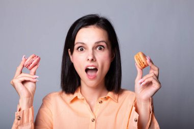 Turuncu gömlekli kadın elinde kurabiye tutuyor.