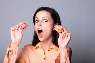 Turuncu gömlekli kadın elinde kurabiye tutuyor.