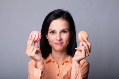 Turuncu gömlekli kadın elinde kurabiye tutuyor.