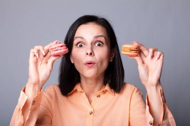 Turuncu gömlekli kadın elinde kurabiye tutuyor.