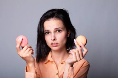 Turuncu gömlekli kadın elinde kurabiye tutuyor.