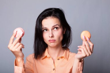 Turuncu gömlekli kadın elinde kurabiye tutuyor.