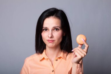 Turuncu gömlekli kadın elinde kurabiye tutuyor.