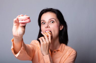 Turuncu gömlekli kadın elinde kurabiye tutuyor.