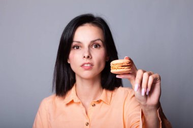 Turuncu gömlekli kadın elinde kurabiye tutuyor.