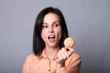 Turuncu gömlekli kadın elinde kurabiye tutuyor.