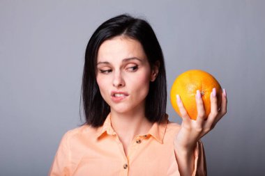 Elinde greyfurt tutan bir kadın.