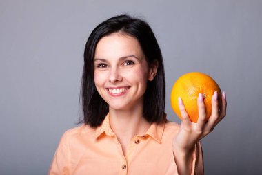 Elinde greyfurt tutan bir kadın.