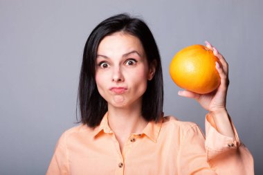 Elinde greyfurt tutan bir kadın.