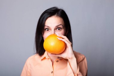 Elinde greyfurt tutan bir kadın.