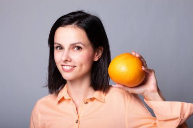 Elinde greyfurt tutan bir kadın.