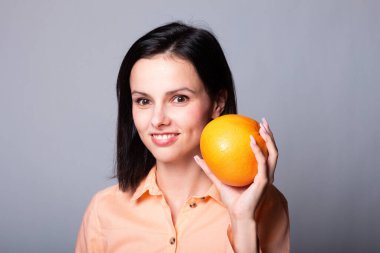 Elinde greyfurt tutan bir kadın.