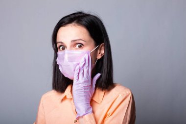 Gömlekli kadın, tıbbi maske ve eldivenler, gri arka plan.