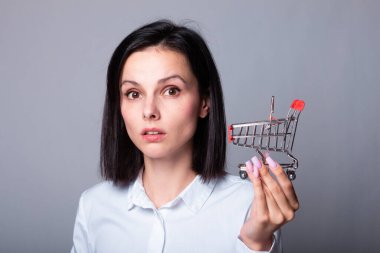 Bir kadın ekonomist elinde küçük bir alışveriş arabası tutuyor.