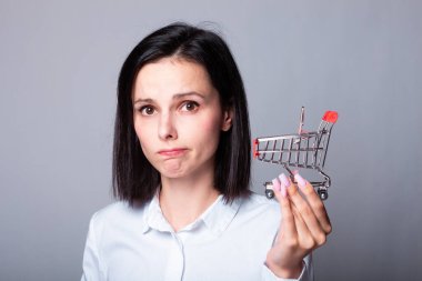 Bir kadın ekonomist elinde küçük bir alışveriş arabası tutuyor.