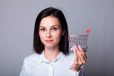 Bir kadın ekonomist elinde küçük bir alışveriş arabası tutuyor.