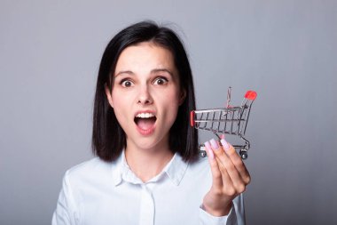 Bir kadın ekonomist elinde küçük bir alışveriş arabası tutuyor.