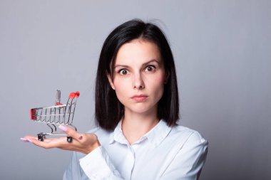 Bir kadın ekonomist elinde küçük bir alışveriş arabası tutuyor.