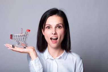 Bir kadın ekonomist elinde küçük bir alışveriş arabası tutuyor.