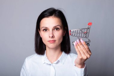 Bir kadın ekonomist elinde küçük bir alışveriş arabası tutuyor.