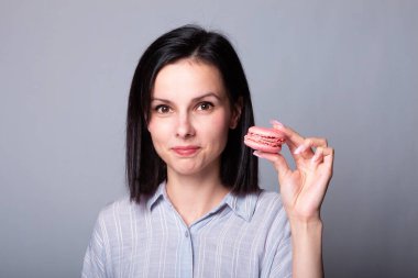 Gömlekli kadın elinde kurabiyeler, gri arka planda.