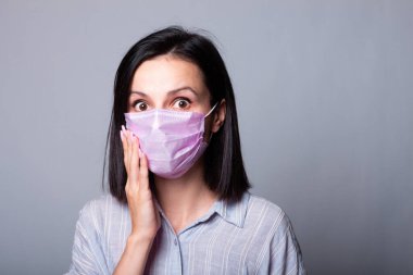 Gömlekli bir kız ve yüzünde pembe bir tıbbi maske.