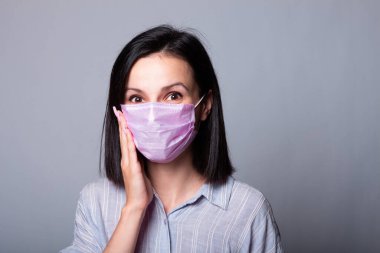 Gömlekli bir kız ve yüzünde pembe bir tıbbi maske.