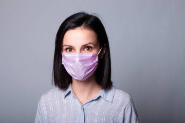 Gömlekli bir kız ve yüzünde pembe bir tıbbi maske.