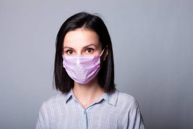 Gömlekli bir kız ve yüzünde pembe bir tıbbi maske.