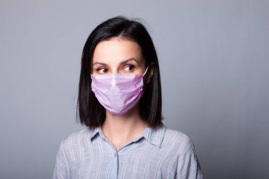 Gömlekli bir kız ve yüzünde pembe bir tıbbi maske.