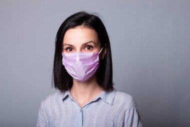 Gömlekli bir kız ve yüzünde pembe bir tıbbi maske.