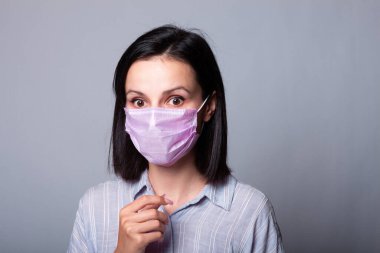 Gömlekli bir kız ve yüzünde pembe bir tıbbi maske.