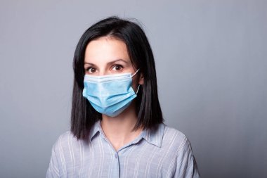 Yüzünde tıbbi maske olan genç bir kadın.