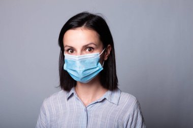 Yüzünde tıbbi maske olan genç bir kadın.