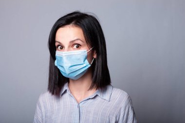 Yüzünde tıbbi maske olan genç bir kadın.