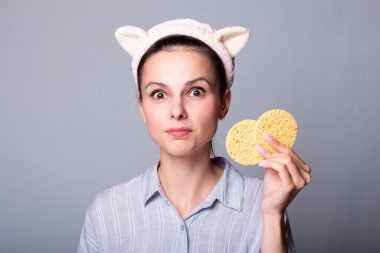 Elinde kozmetik süngerler tutan komik kadın.