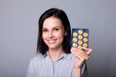 Güzel bir kız elinde bir paket hap tutuyor.