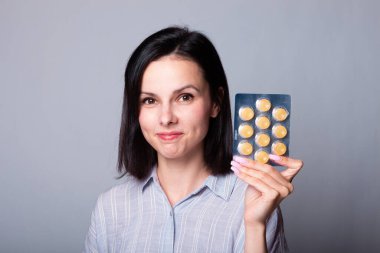 Güzel bir kız elinde bir paket hap tutuyor.