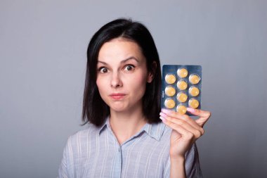 Güzel genç bir kız elinde bir paket hap tutuyor.