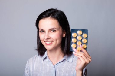 Elinde bir paket hap tutan bir kadın.