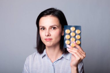 Elinde bir paket hap tutan bir kadın.