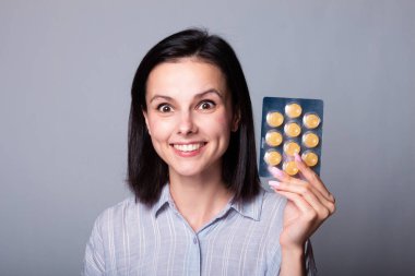 Elinde bir paket hap tutan bir kadın.