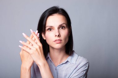 Kadın ellerini gösteriyor, gri stüdyo geçmişi var.